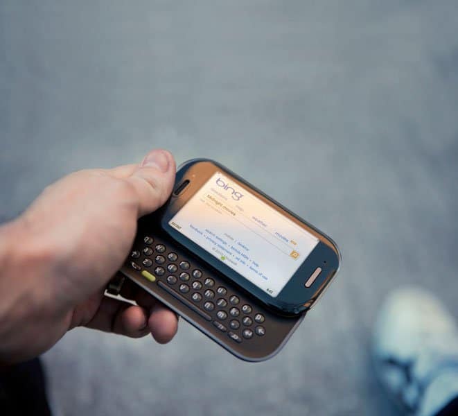 Sharp Kin Two held in hand, displaying email inbox on screen with slide-out QWERTY keyboard visible