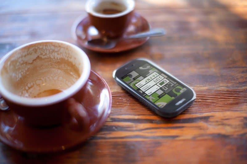 Sharp Kin Two smartphone on wooden table next to coffee cups with latte art