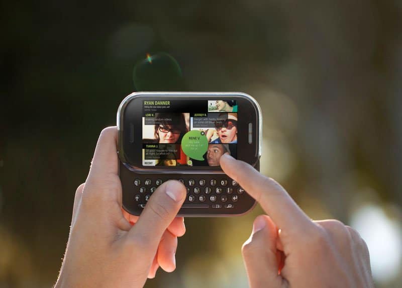 Sharp Kin Two held in hands, displaying contact profile grid on screen with photos and names including Ryan Danner