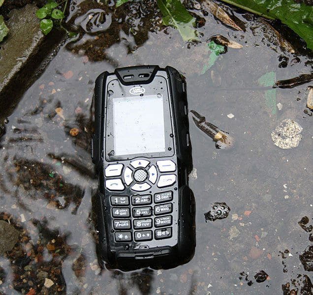 Sonim Land Rover S1 rugged mobile phone with numeric keypad, viewed from above on wet ground