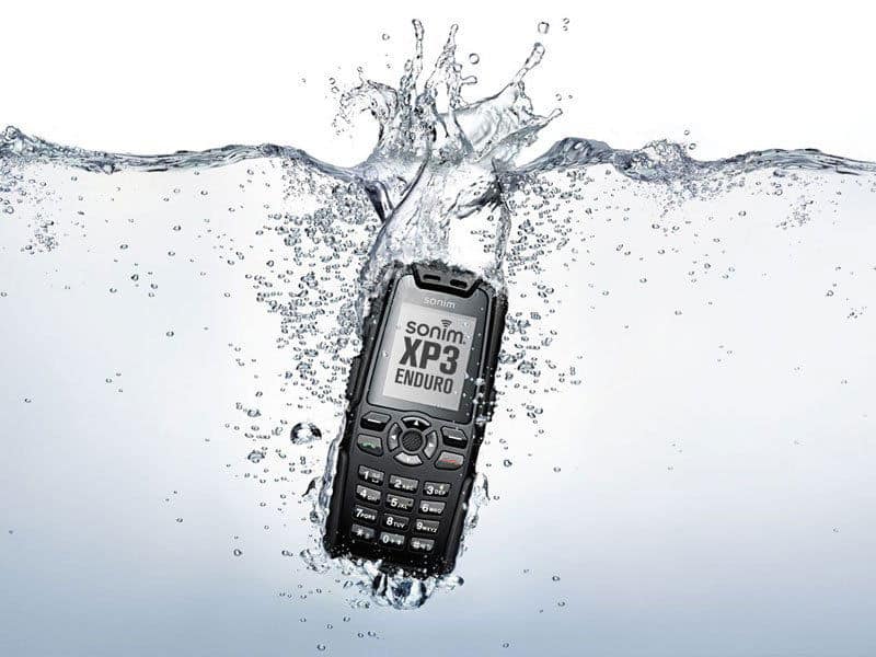 Front view of a black Sonim XP3 Enduro phone partially submerged in water, showcasing its water resistance.