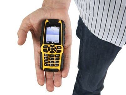 Front view of Sonim XP3 Enduro cell phone, screen and buttons visible, held in hand by person in striped shirt and dark pants.