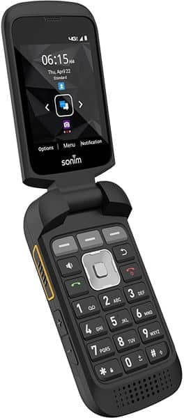 Sonim XP3plus flip phone shown open, displaying time and date on upper screen with navigation menu, lower keypad with numeric buttons and speaker grille visible