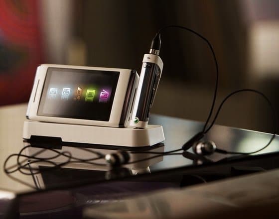 Sony Ericsson Aino on docking station with headphones, screen displaying colorful app icons