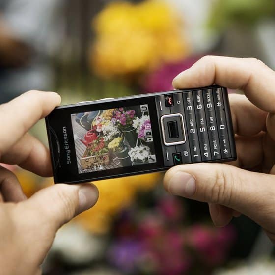 Sony Ericsson Elm phone held in hands, displaying flower photo on screen, with numeric keypad visible